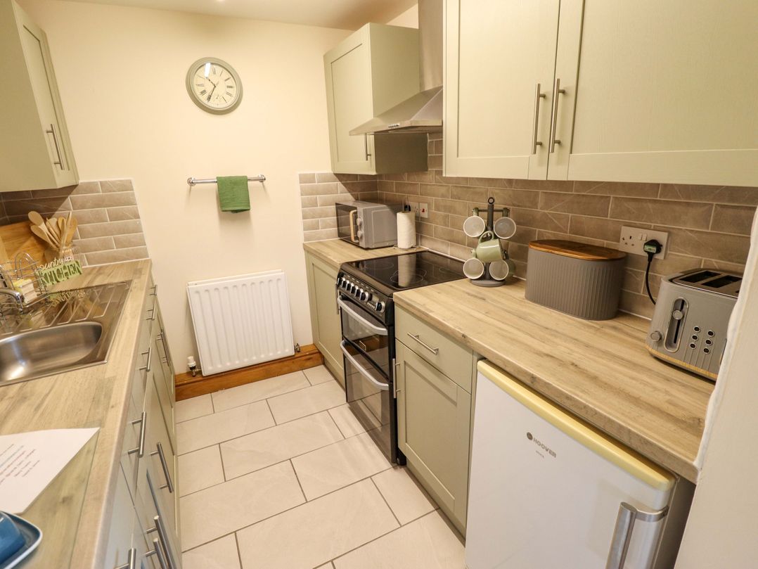 A kitchen with a sink, cooker, and fridge at Barn Owl near Louth