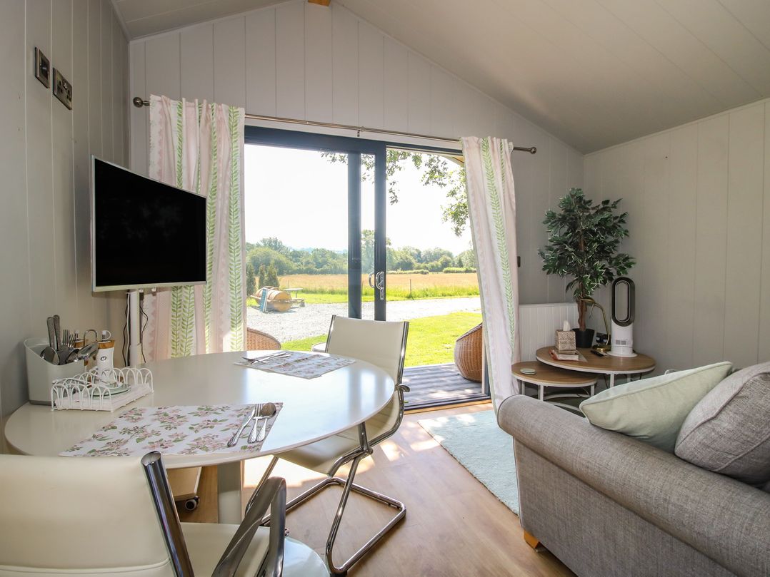 A living room with a dining table and television at Leafy Oaks Cabin in Munslow