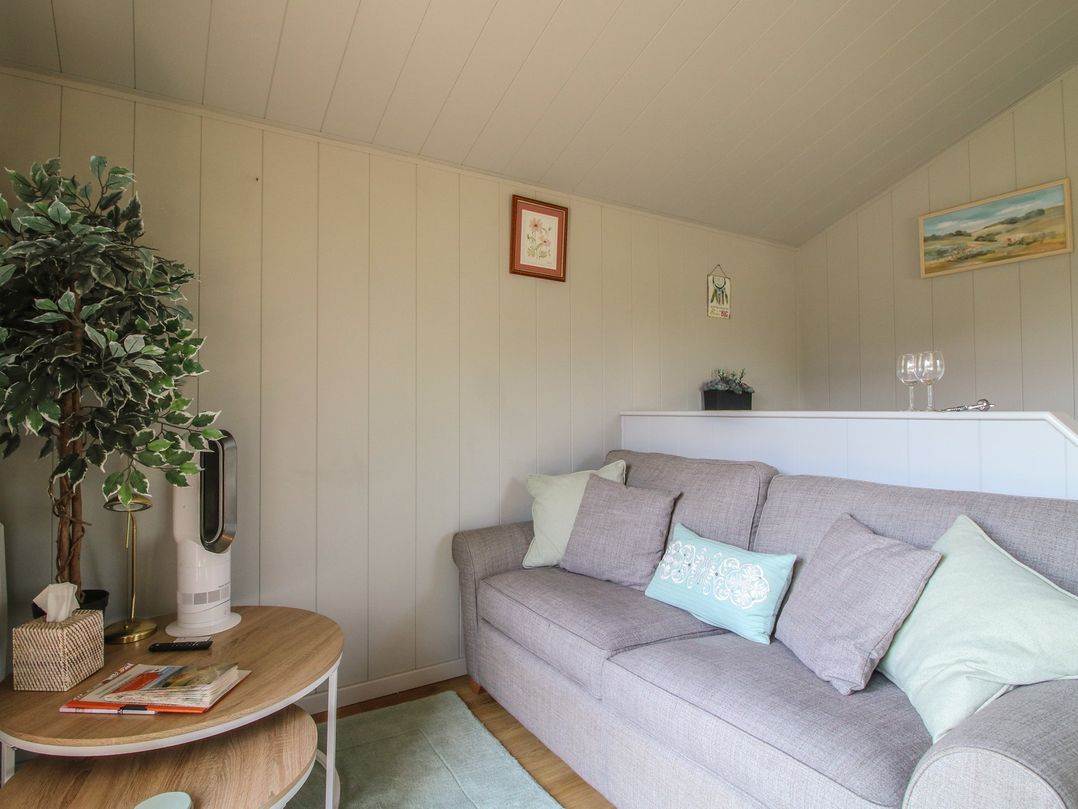 A living room with a sofa and coffee table at Leafy Oaks Cabin in Munslow