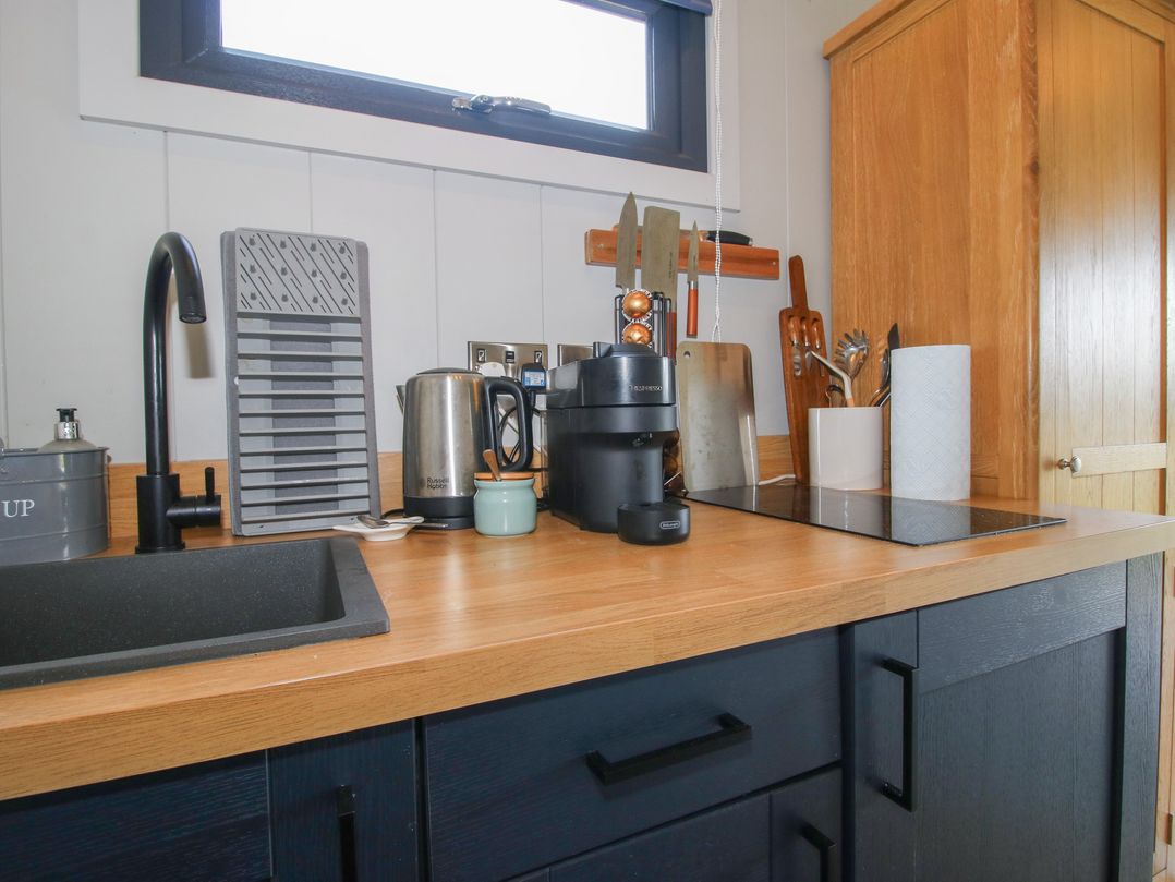 A kitchen with a sink and various appliances at Leafy Oaks Cabin Munslow