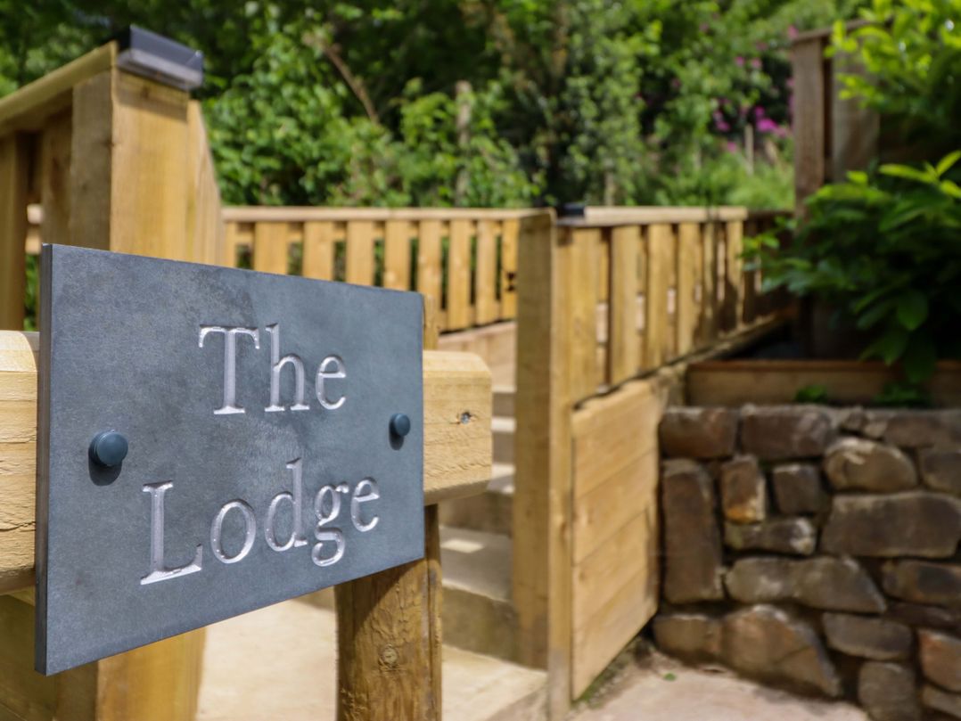 A sign for The Lodge in an outdoor area near steps and a stone wall at Lodge at Nadur Commins Coch near Machynlleth