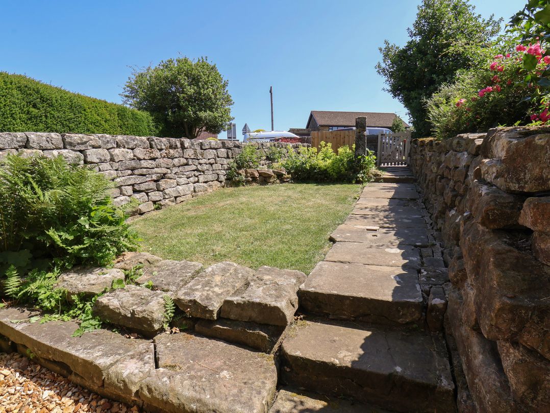 A garden with a stone wall and plants at 4 Lilac Cottages Ainthorpe