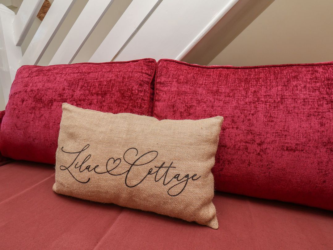 A sofa with red cushions and a decorative pillow at 4 Lilac Cottages Ainthorpe