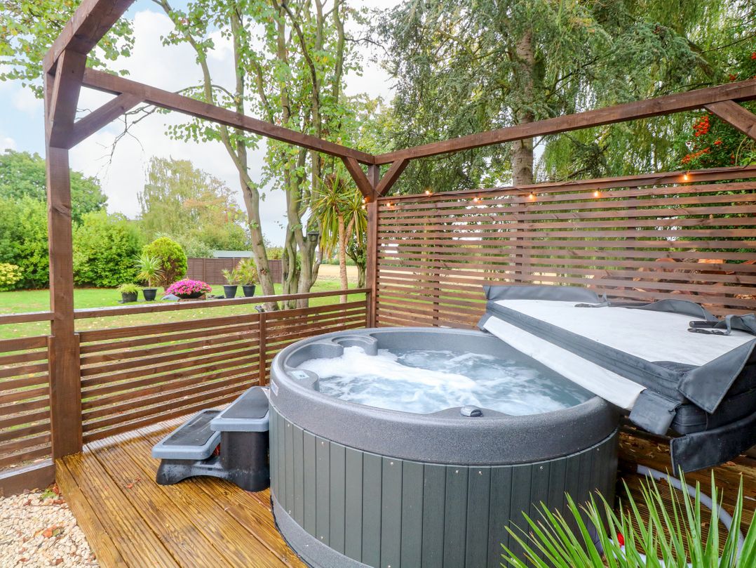 A hot tub on wooden decking in a garden at Three Ways South Lopham near Garboldisham