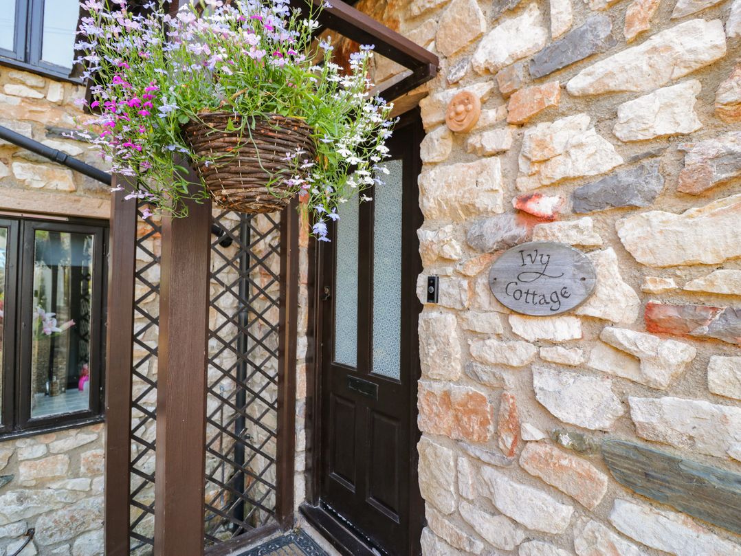An entrance with a door and flower basket at Ivy Cottage Abergele
