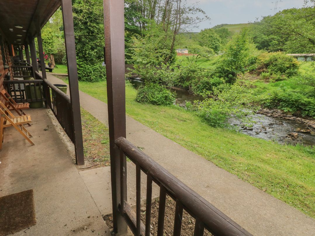 An outdoor area with a pathway, river, and chairs at Cabin No. 10 - Salt and Fern Cabins in Goytre near Port Talbot