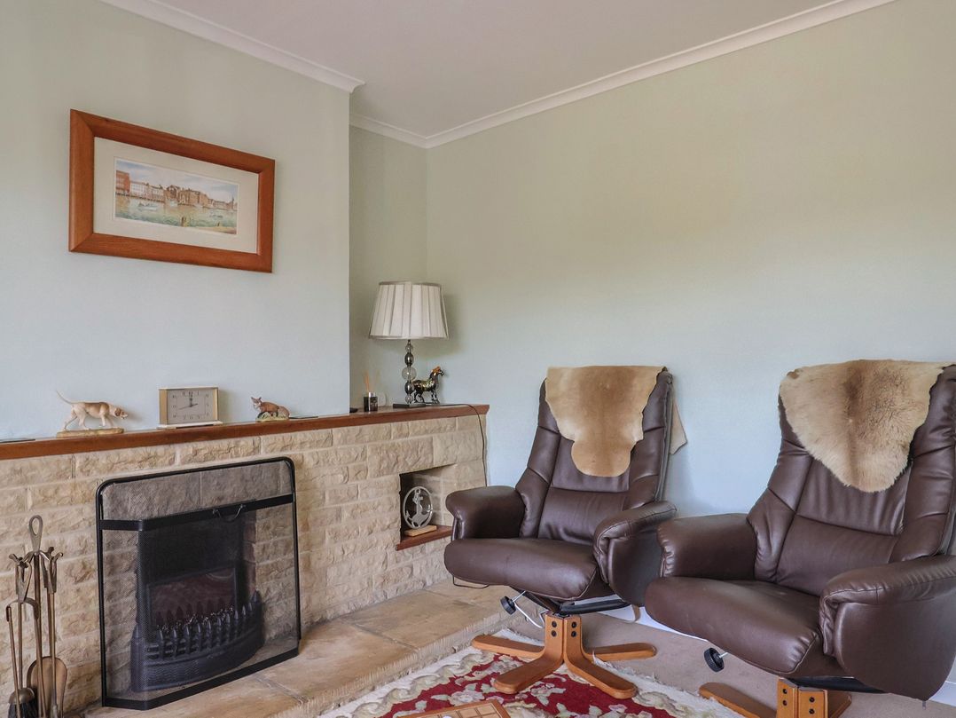 A sitting room with two armchairs and a fireplace at Tane Winterborne Stickland