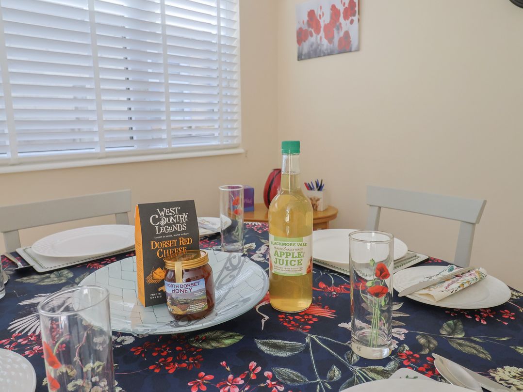 A dining table set with plates, glasses, cheese, honey, and apple juice at Tane in Winterborne Stickland