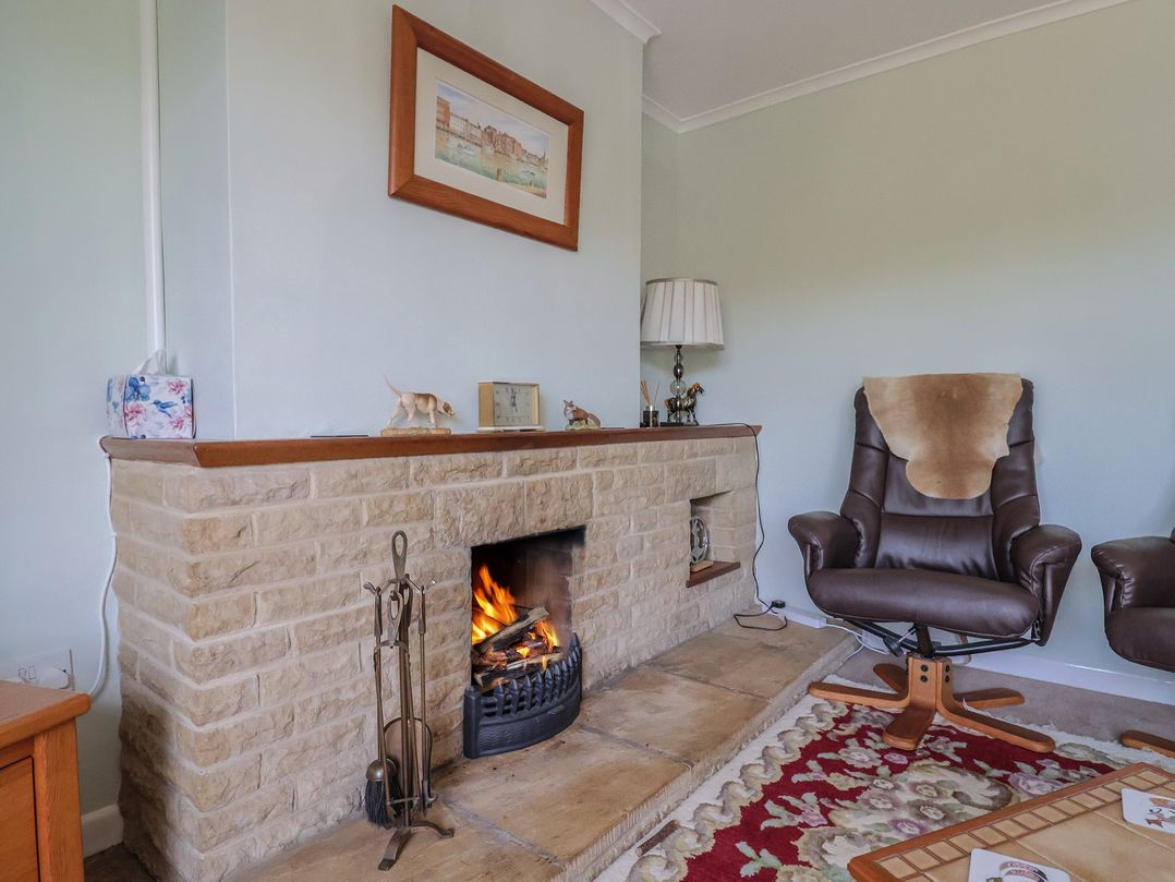 A living room with a fireplace and armchair at Tane in Winterborne Stickland