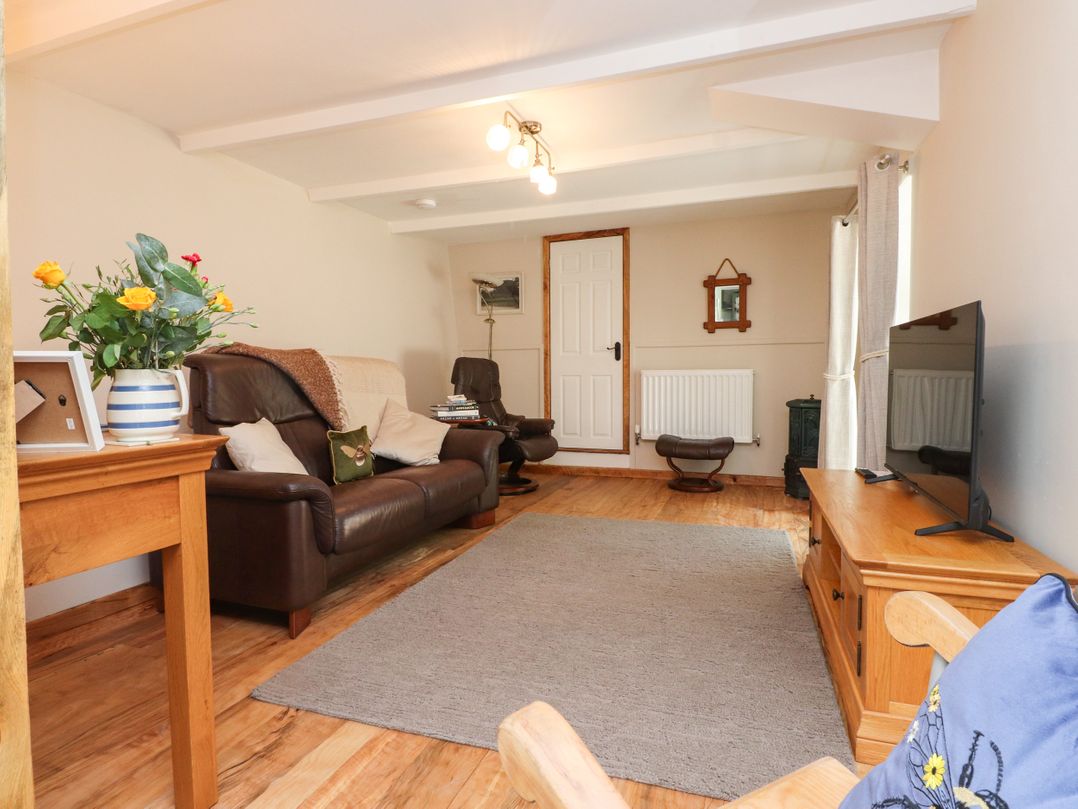 A living room with a sofa, television, and coffee table at Woodman's Lodge in Llanallgo near Moelfre