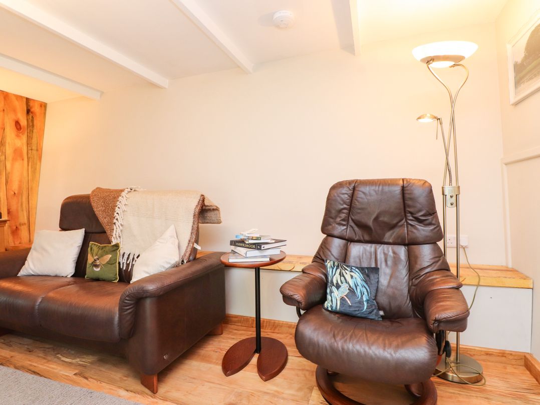 A living room with a sofa and armchair at Woodman's Lodge in Llanallgo near Moelfre