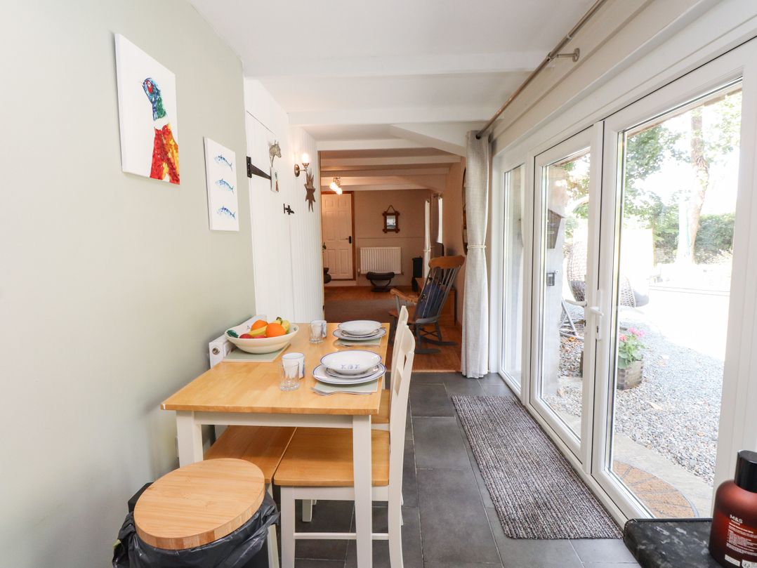 A kitchen with a table and chairs at Woodman's Lodge in Llanallgo near Moelfre