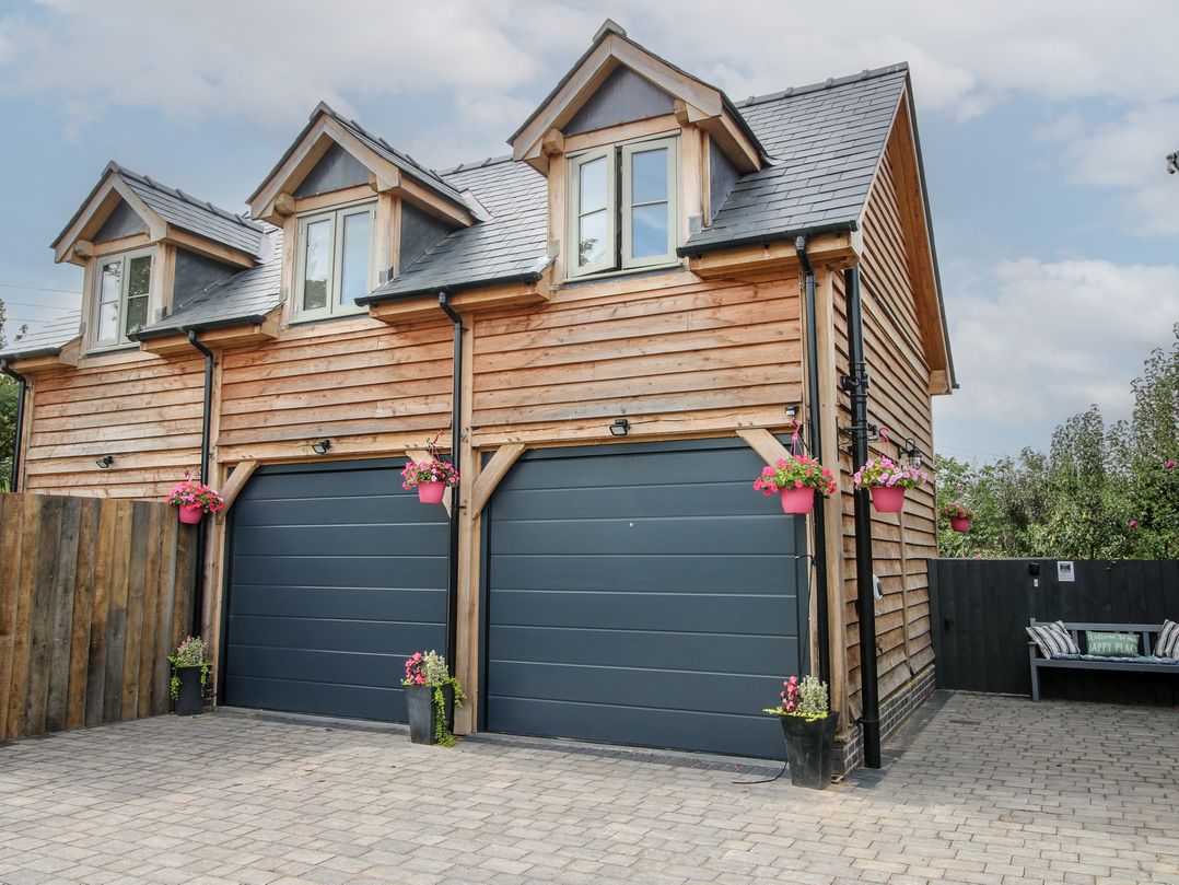 A garage with flower pots and a paved driveway at Little Acre in Leominster