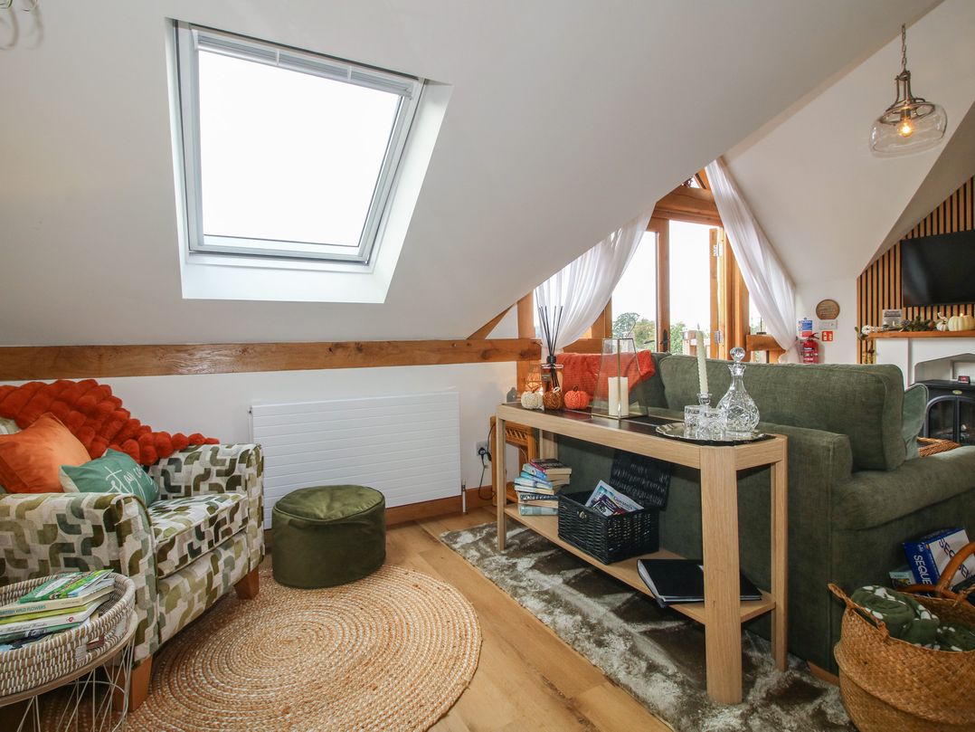 A living room with armchair, sofa, and coffee table at Little Acre in Leominster
