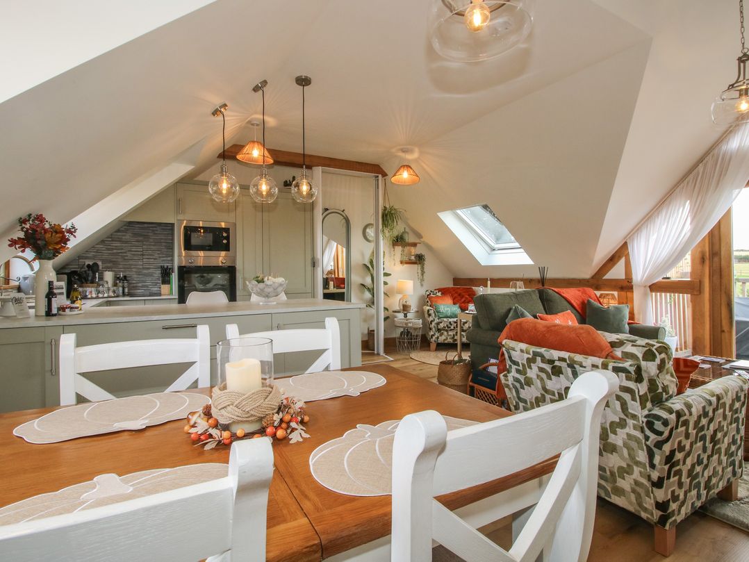 A living area with a dining table and kitchen in Little Acre Leominster
