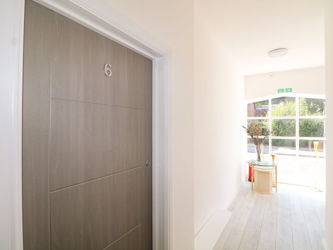 A hallway with a door marked 6 and a table with a plant at 2 Bed in Bishop's Waltham