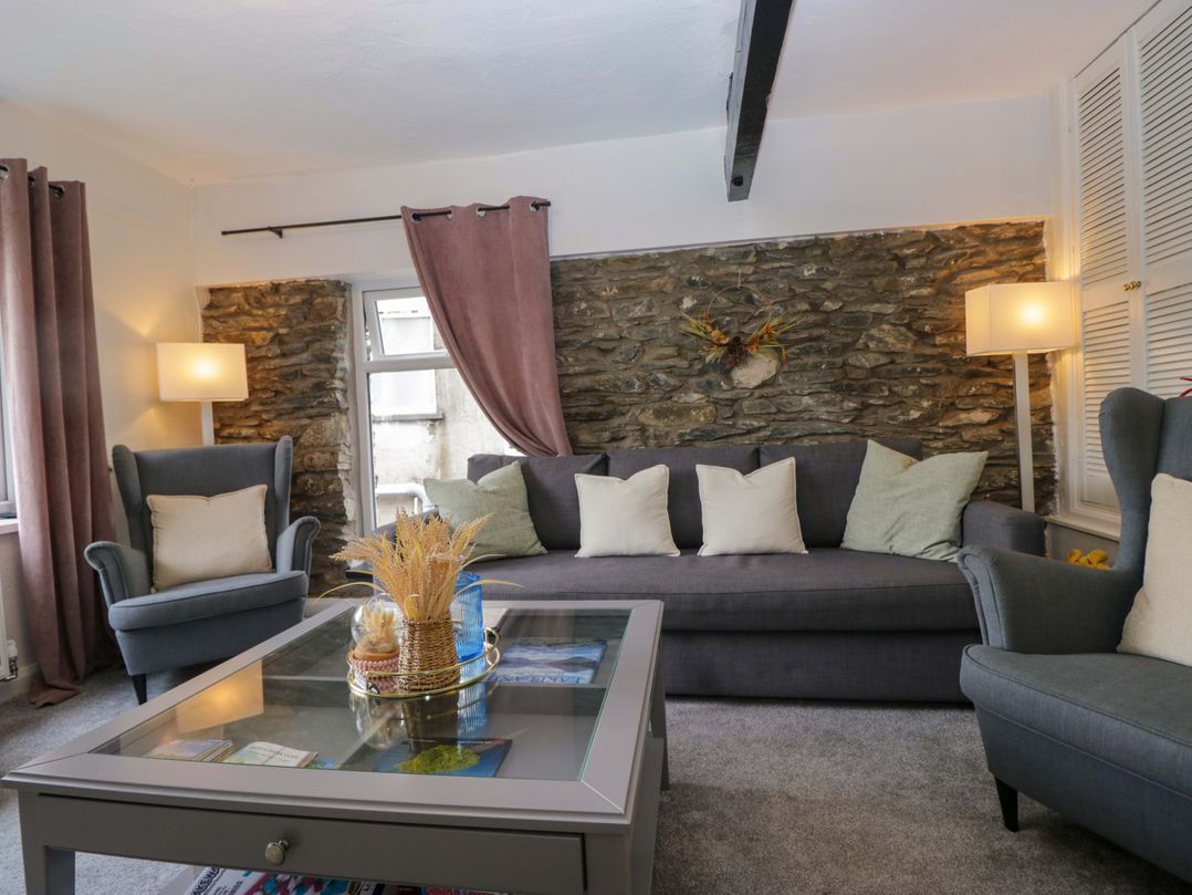 A living room with a gray sofa and armchair at Courtyard Cottage in Cartmel