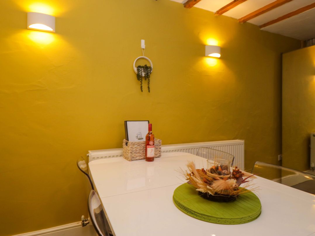 A dining room with a table and a wine bottle at Courtyard Cottage in Cartmel