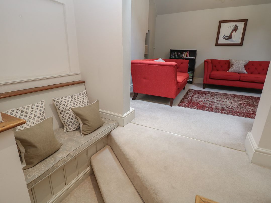 A living room with red sofas and a staircase at Lion House in Ashbourne
