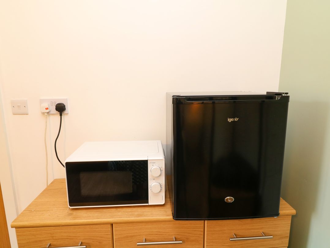 A microwave and refrigerator on a cabinet at Walcott Lodges - Catley, Billinghay, Lincolnshire
