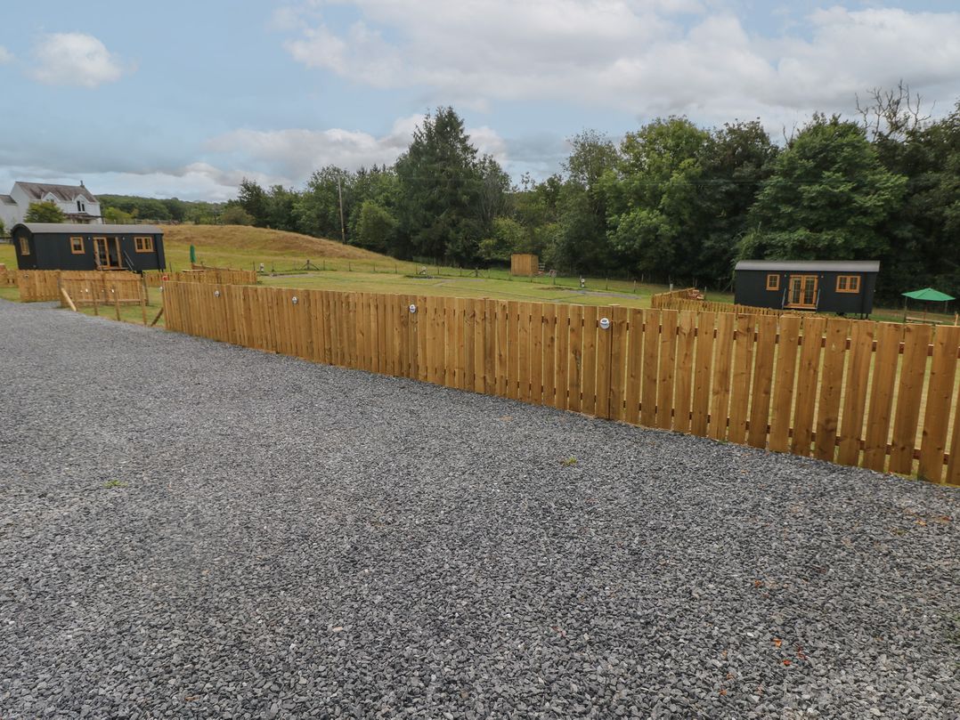 An outdoor area with gravel and tiny houses near a wooden fence at Cwtch Y Bugail 2 Near Llandeilo