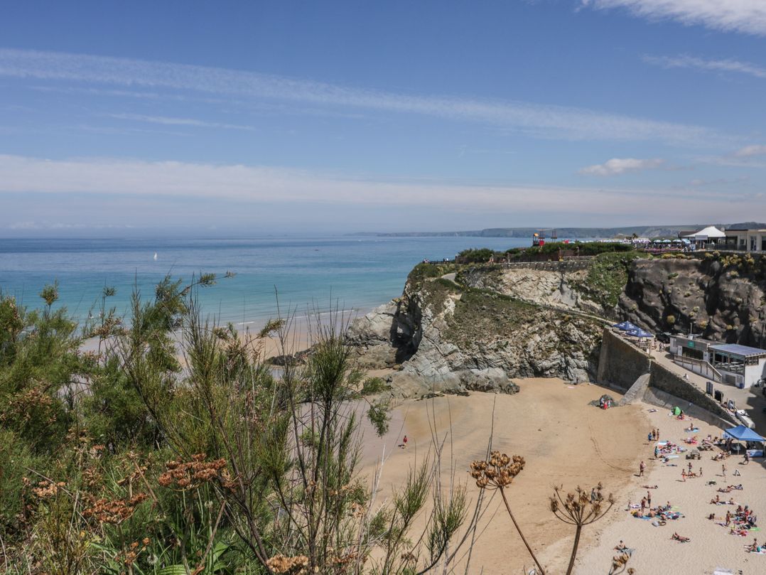 A beach with people and cliffs at Shoreline Apartment No.8 in Newquay