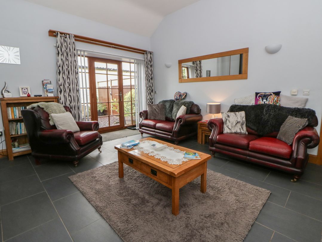 A living room with two sofas, a coffee table, and a bookshelf at Yr Hen Llaethdy near Newcastle Emlyn