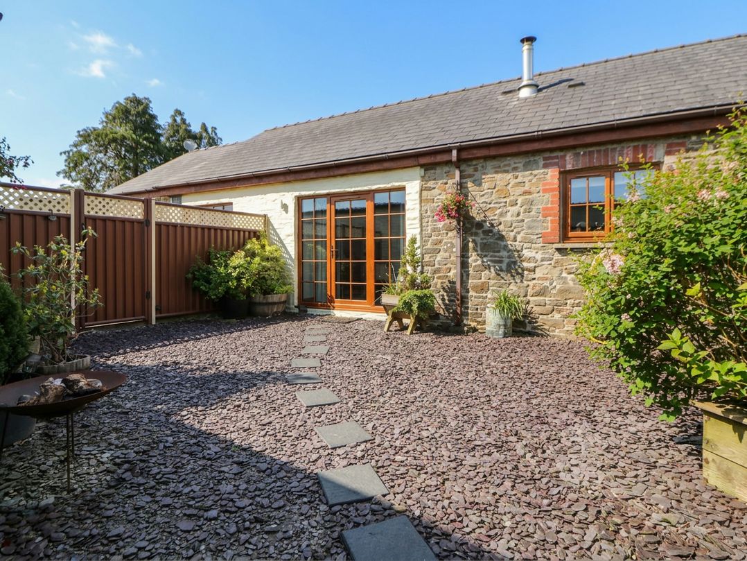 A garden with a stone wall and flower pots at Yr Hen Llaethdy near Newcastle Emlyn