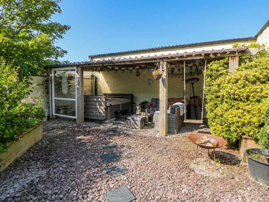 An outdoor garden with seating and a hot tub at Yr Hen Llaethdy in Blaen-Cil-Llech near Newcastle Emlyn