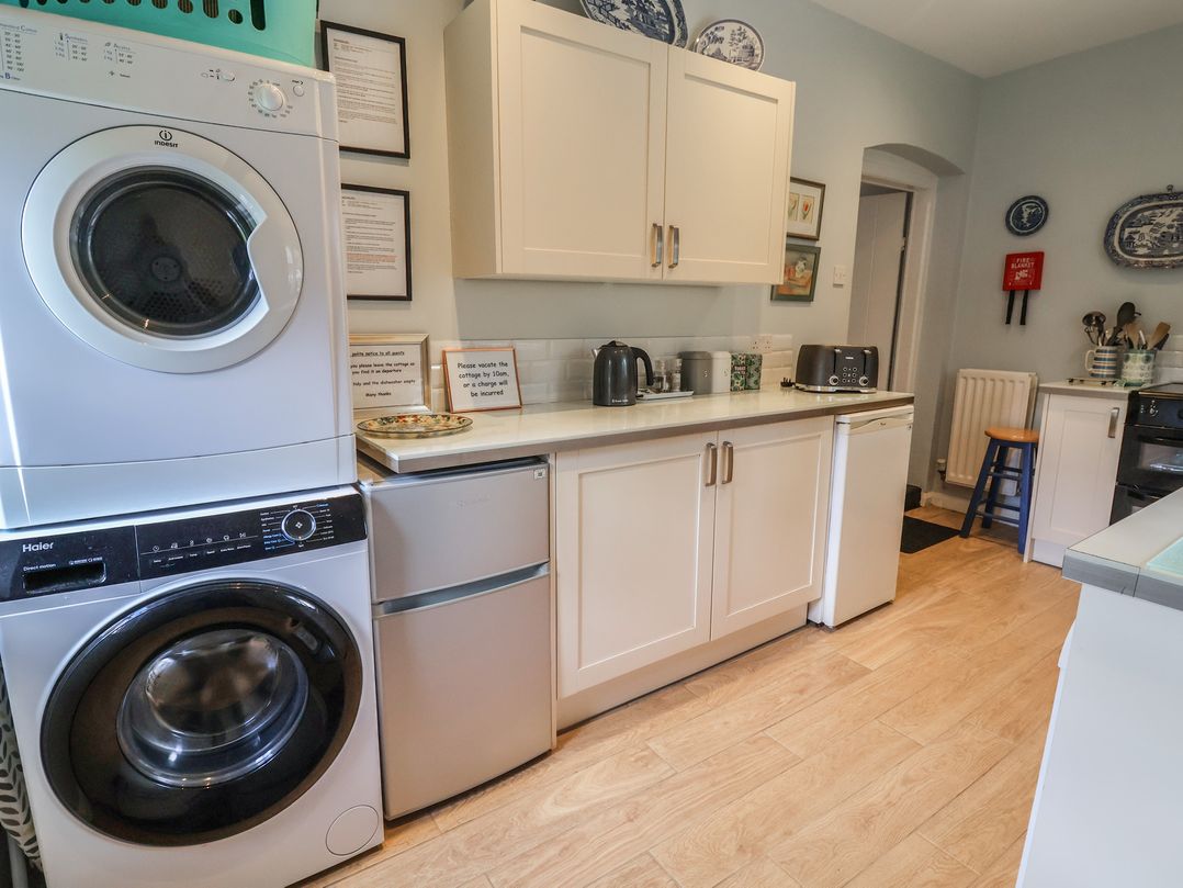 A kitchen with appliances including a washing machine and refrigerator at Wolvesacre Mill Cottage Agden near Whitchurch
