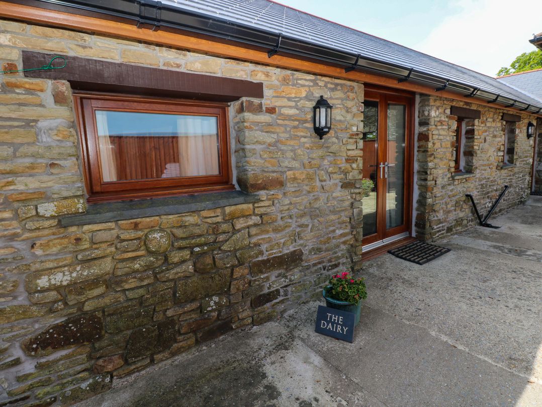 An exterior view featuring a stone wall and entrance door at The Dairy near Penuel Llanmorlais