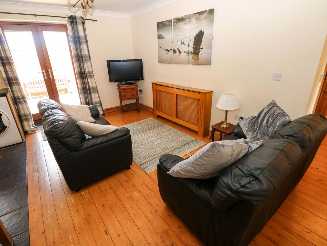 A living room with a sofa and television at The Dairy in Penuel near Llanmorlais