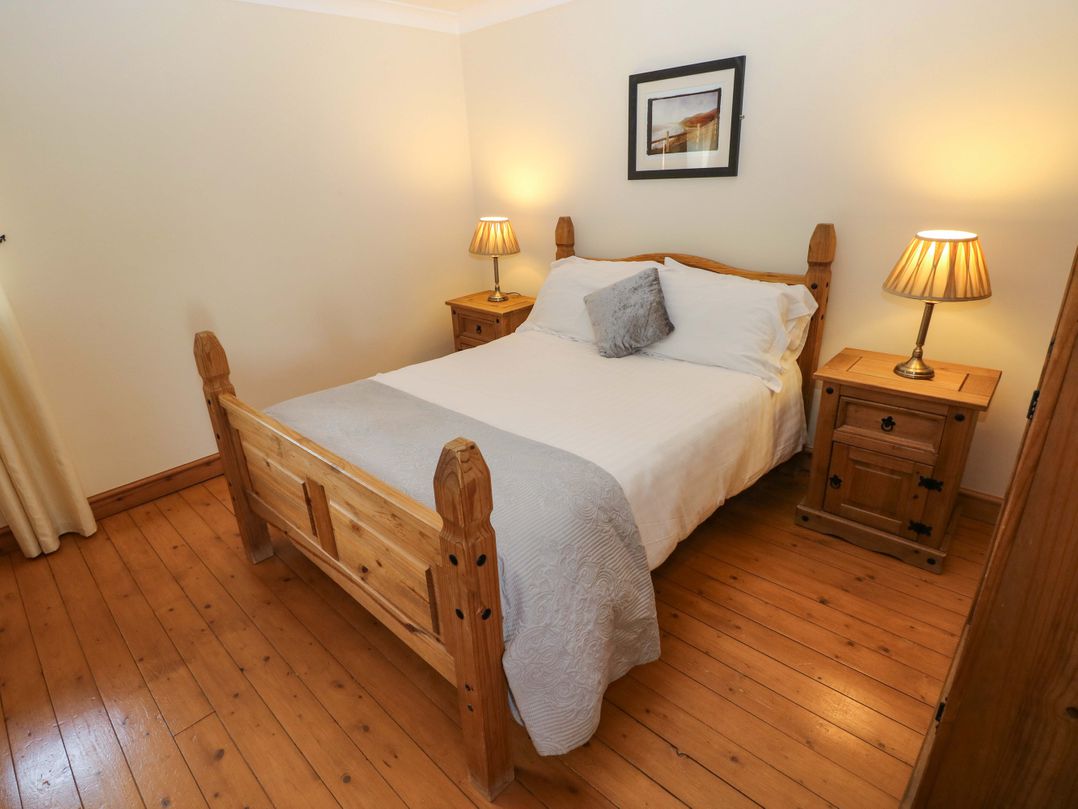 A bedroom with a bed and nightstands at The Dairy in Penuel near Llanmorlais