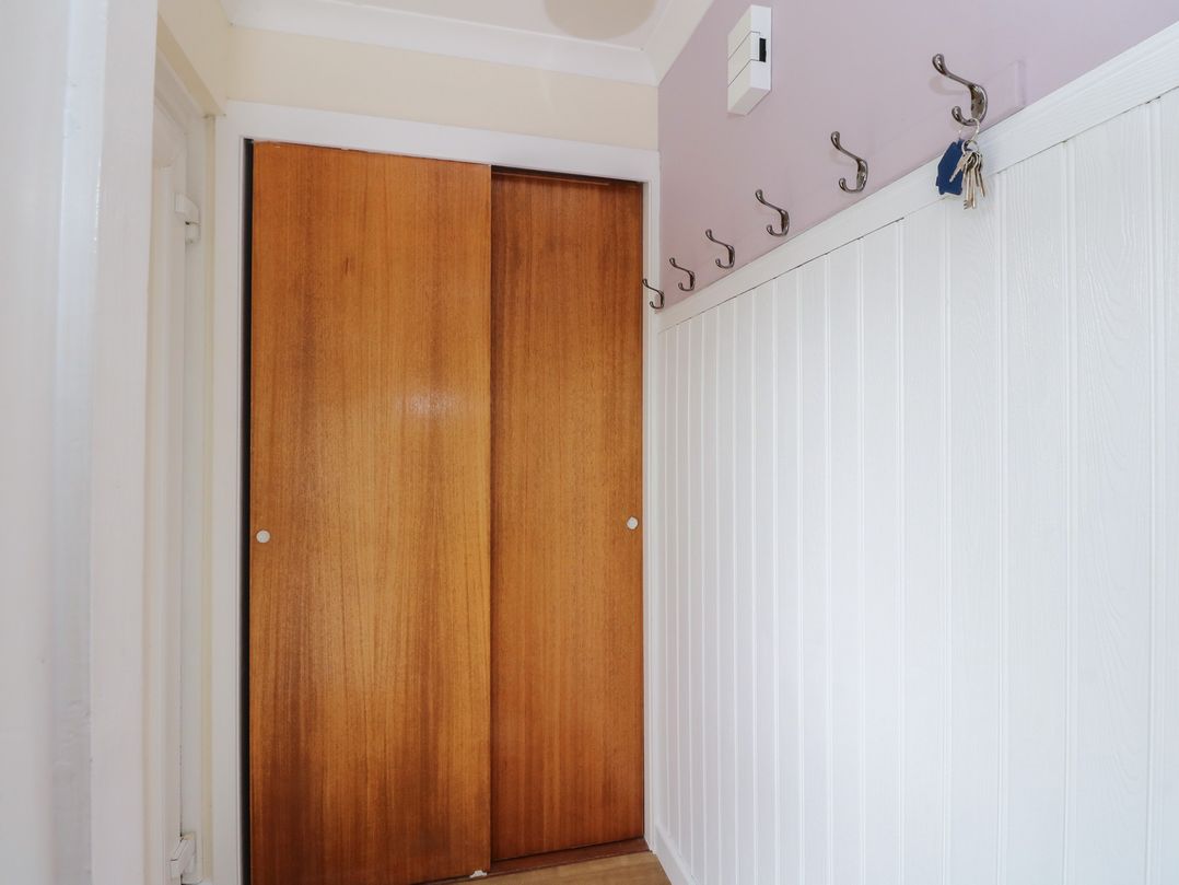 A hallway with sliding doors and coat hooks at Steam Cottage in Aviemore