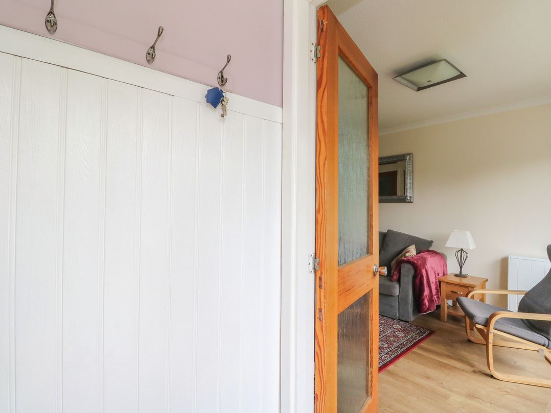 A hallway with coat hooks and a door at Steam Cottage in Aviemore