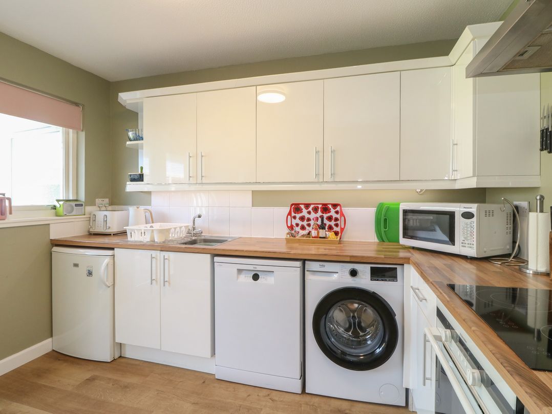 A kitchen with appliances and cabinetry at Steam Cottage in Aviemore