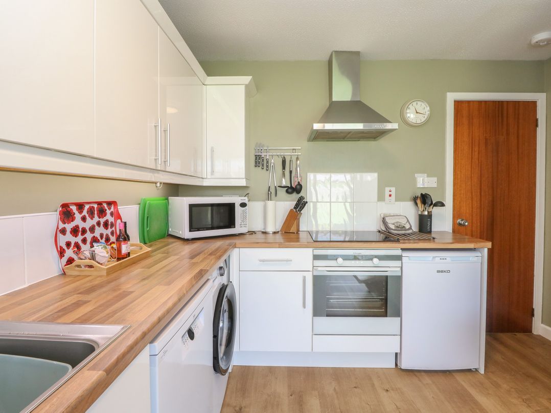 A kitchen with cabinets, microwave, oven, and sink at Steam Cottage in Aviemore