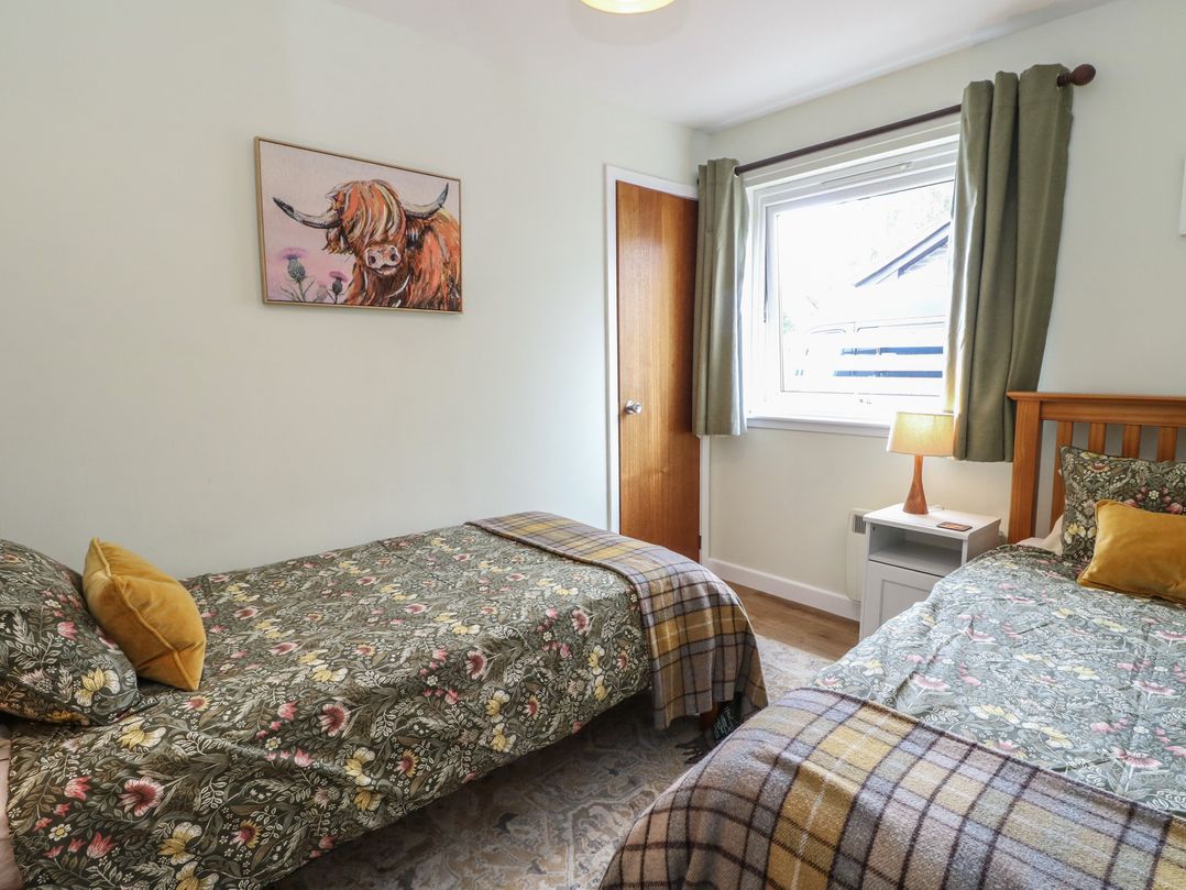 A bedroom with two single beds and a painting at Steam Cottage in Aviemore