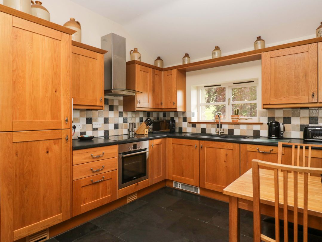 A kitchen with wooden cabinets and appliances at Copper Beech Cottage in Torver