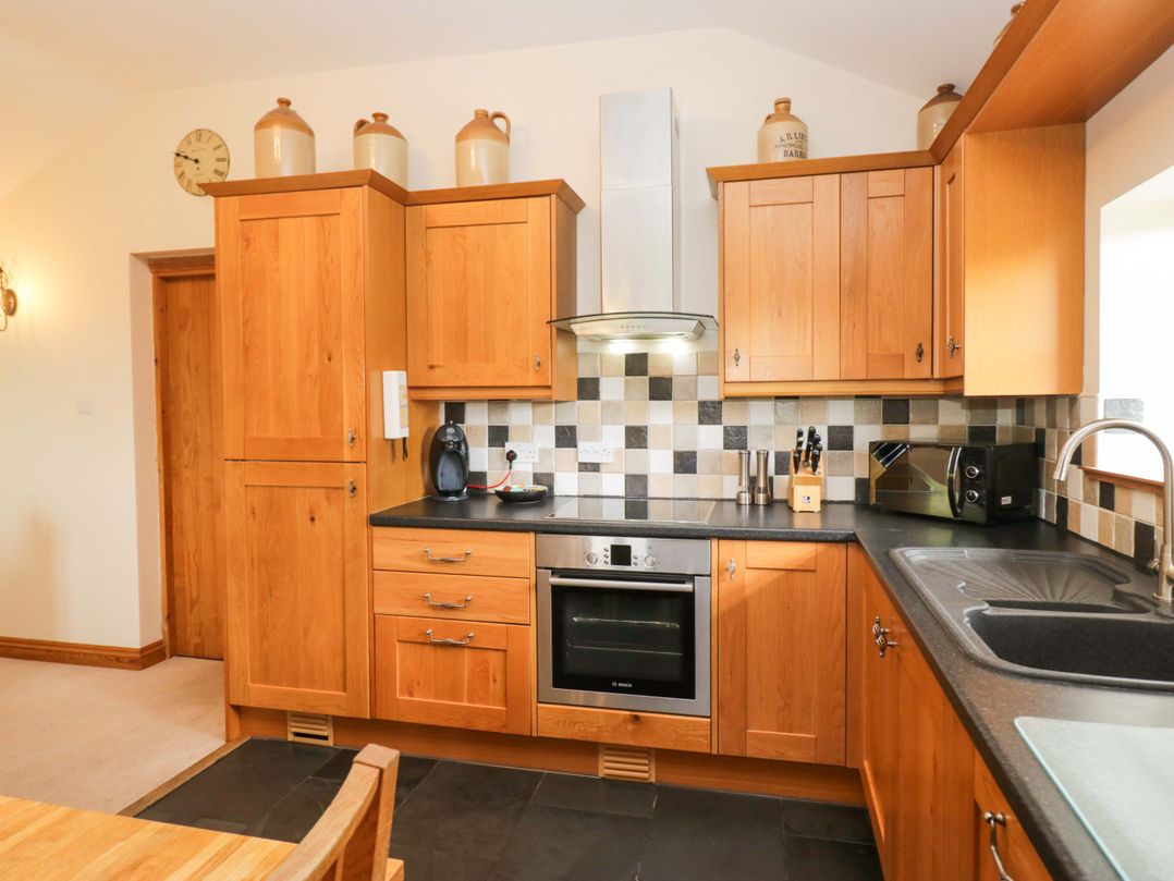 A kitchen with cabinets and appliances at Copper Beech Cottage in Torver