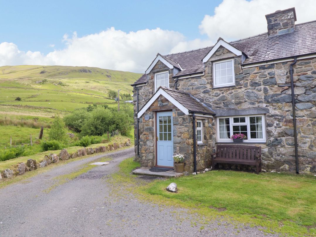 A cottage with a blue door and bench at Stabal Cottage in Dolgellau