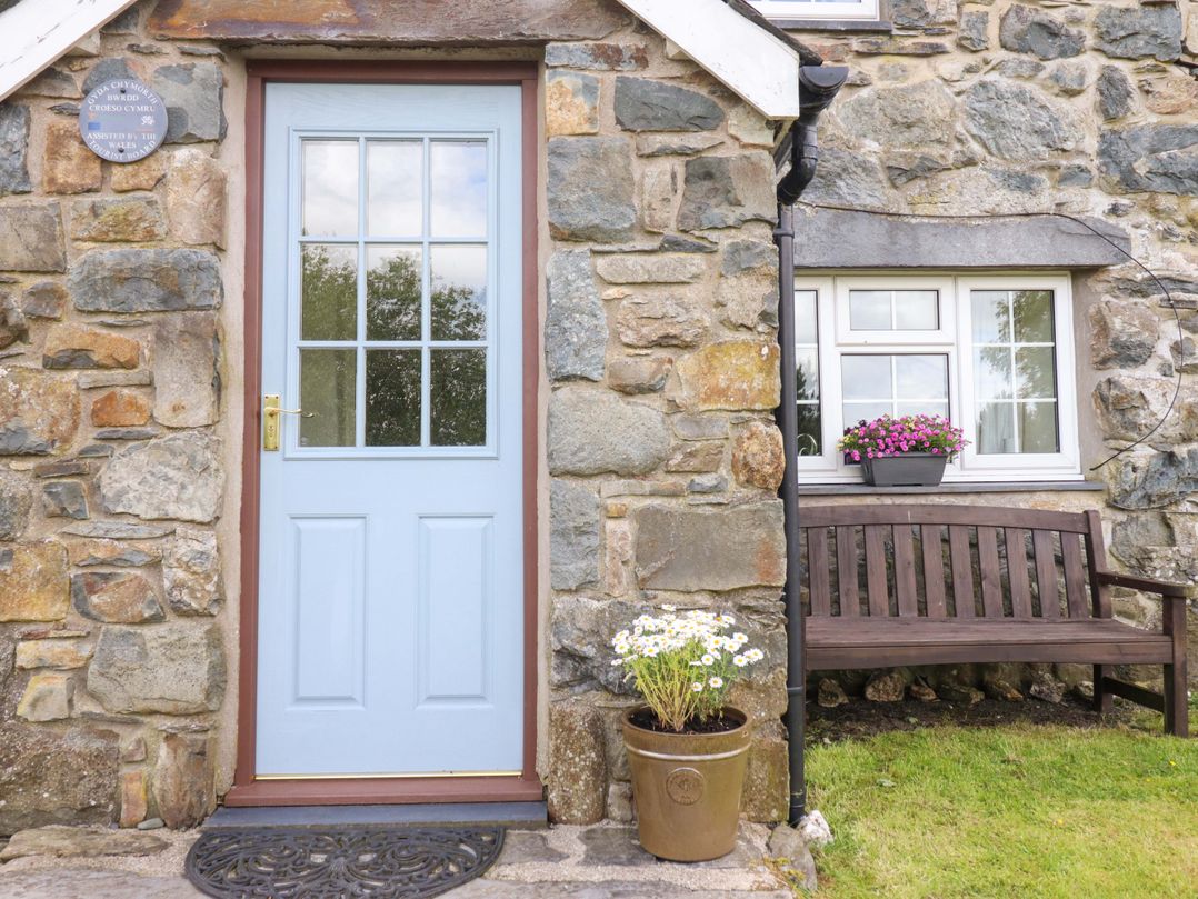 An exterior view of a house with a blue door and stone wall at Stabal Cottage in Dolgellau