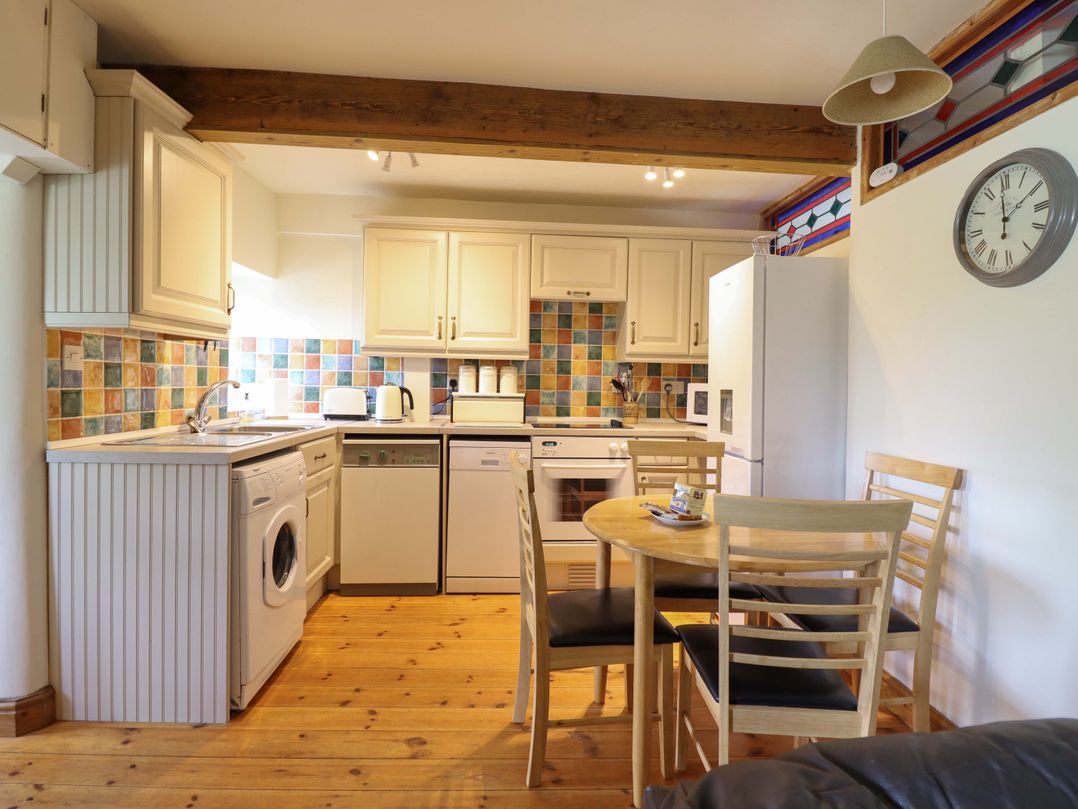 A kitchen with appliances and a dining table at Stabal Cottage in Dolgellau