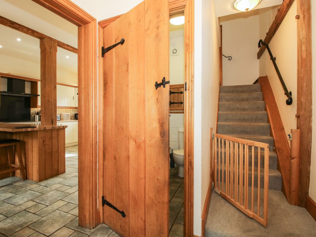 A hallway with a staircase and a bathroom door at Trooper's Barn in Westhope