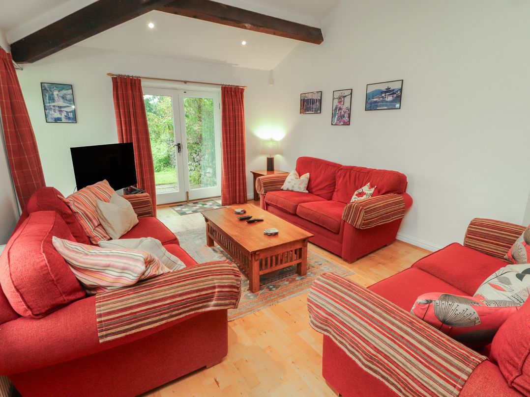 A living room with red sofas and a coffee table at Winster Fields in Cartmel Fell near Windermere