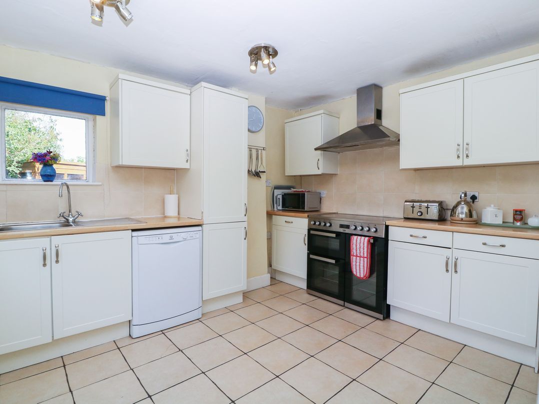 A kitchen with white cabinets and appliances at The Lock House in Gloucester