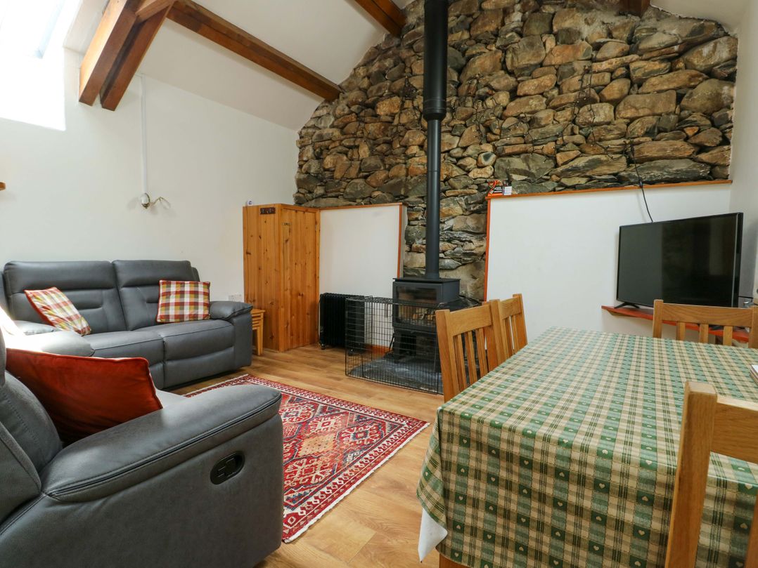 A living room with a sofa, television, and dining table at Bythyn Ddol Hafod in Capel Curig