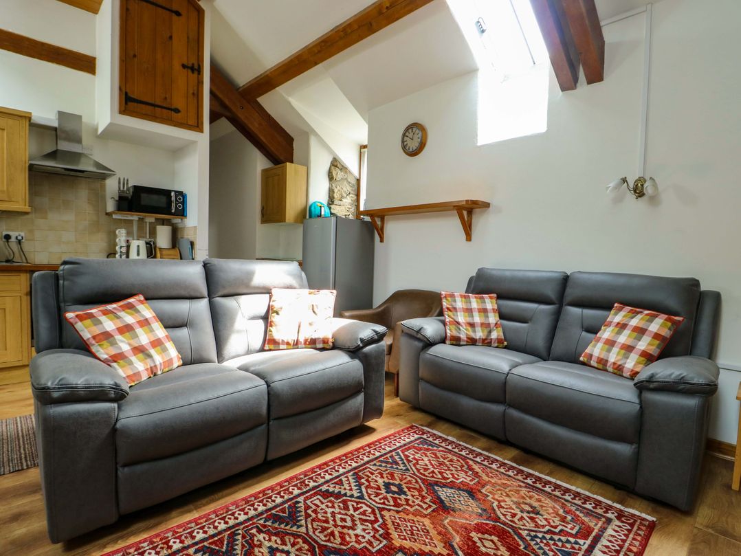 A living room with sofas and kitchen appliances at Bythyn Ddol Hafod in Capel Curig