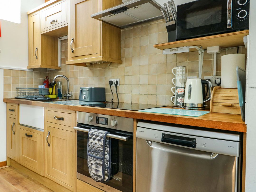 A kitchen with cabinets, sink, and appliances at Bythyn Ddol Hafod in Capel Curig