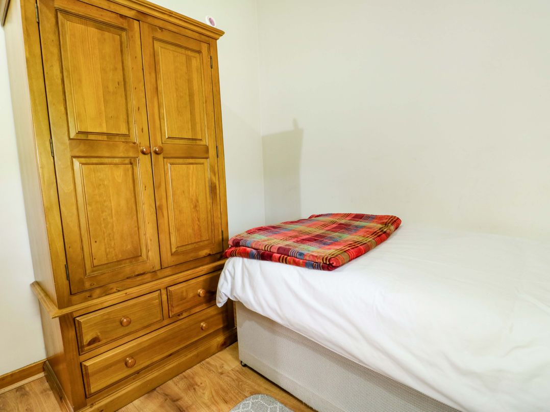 A bedroom with a wooden wardrobe and a bed at Bythyn Ddol Hafod in Capel Curig